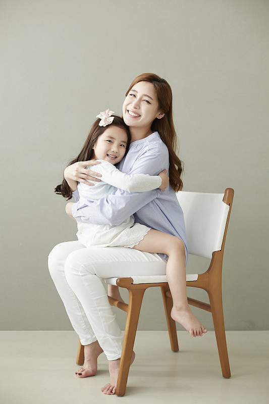 女儿和母亲坐在椅子上看起来很开心的照片摄影图片