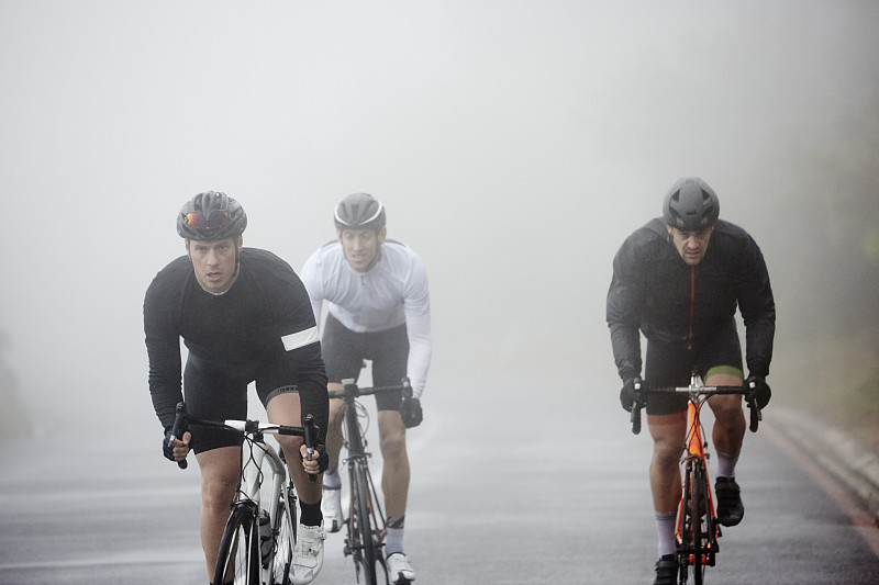 在雨天的道路上骑自行车的男性图片下载