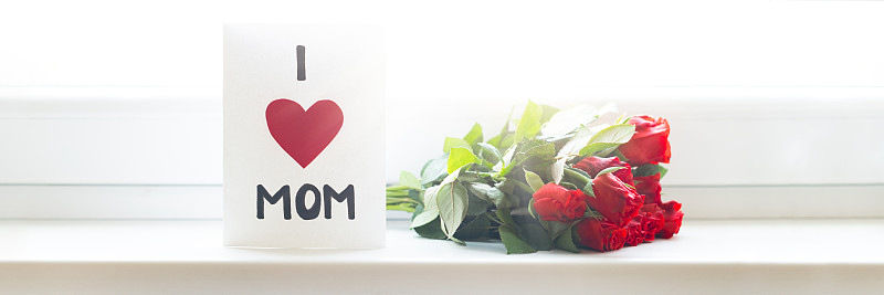 母亲节快乐或生日横幅自制贺卡和窗户上的一束红玫瑰图片下载