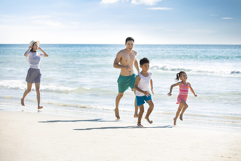 快乐的年轻家庭在沙滩奔跑图片下载