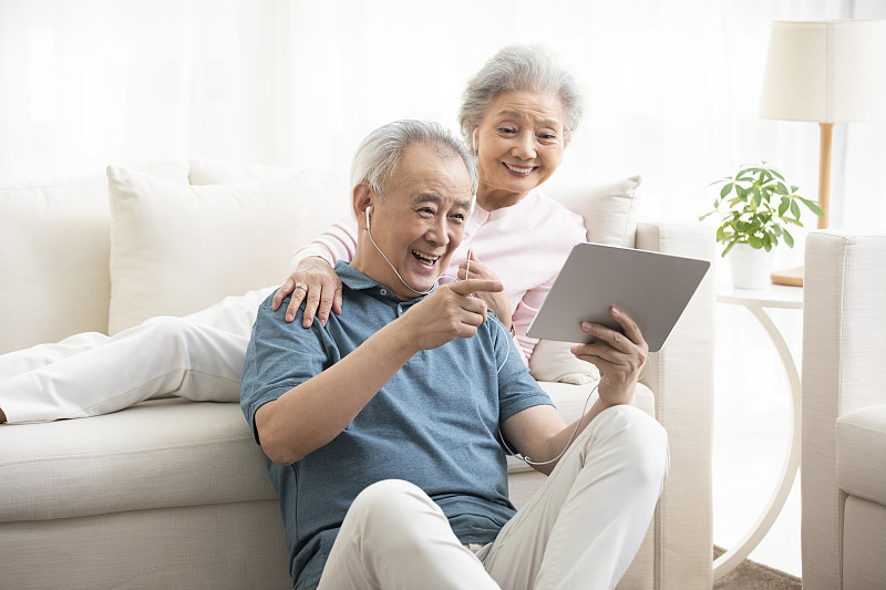 快乐的老年夫妇在客厅使用平板电脑图片下载