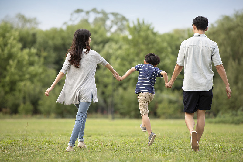 快乐年轻家庭在草地上散步图片素材