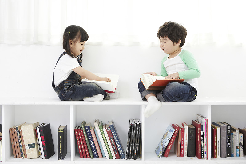 男孩和女孩坐在书架上的照片摄影图片下载