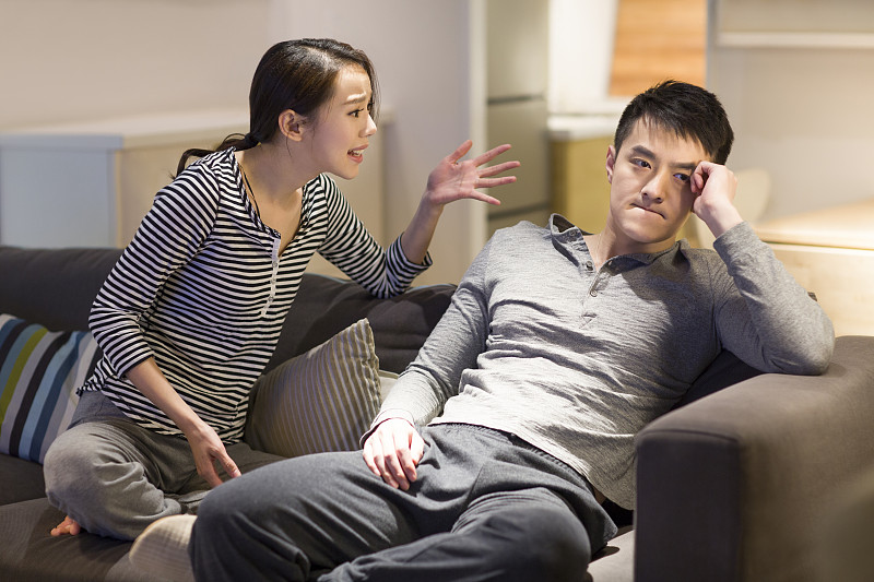 年轻情侣在客厅沙发上争吵图片素材