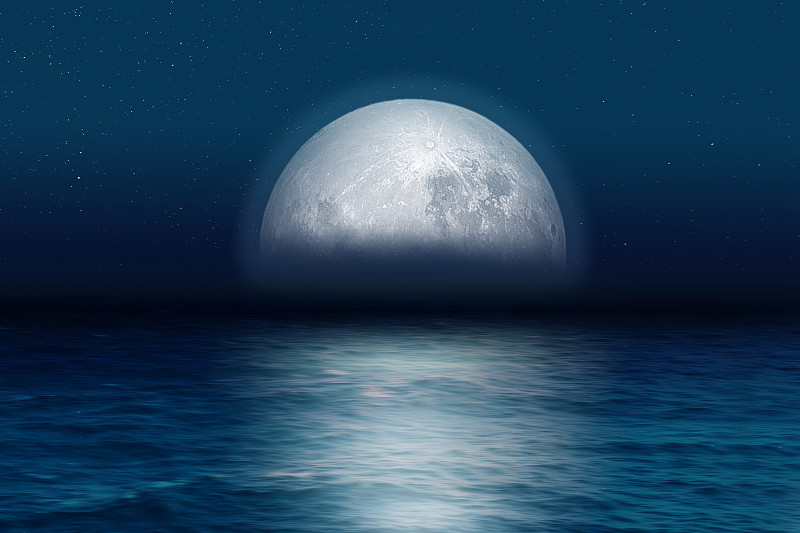 蓝月亮在夜晚从海上升起。图片下载