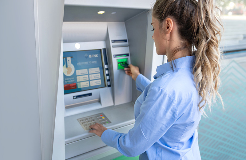 快乐的女人在自动取款机上取钱图片素材