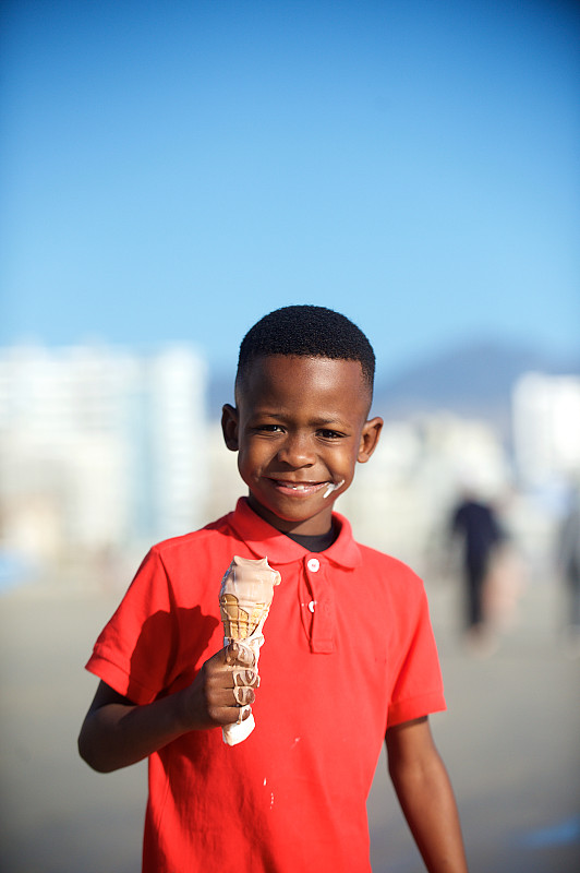 海滩上的男孩拿着冰淇淋看着照相机图片下载