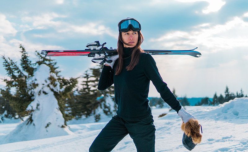 手持滑雪板在山上行走的女人图片下载