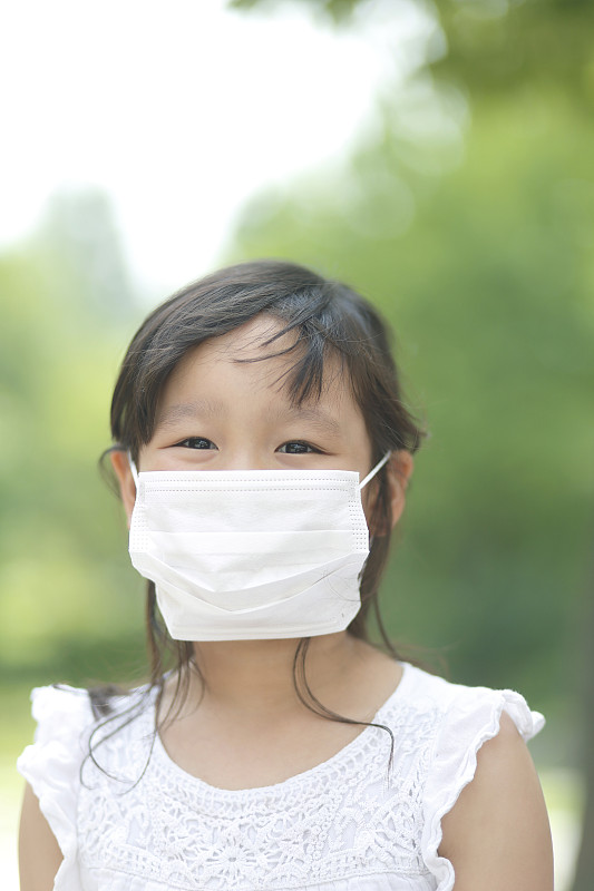 戴着流感口罩的小女孩在公园里图片下载