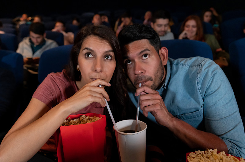 一对幸福的情侣在看电影，一个女人在吃东西，一起喝酒图片下载
