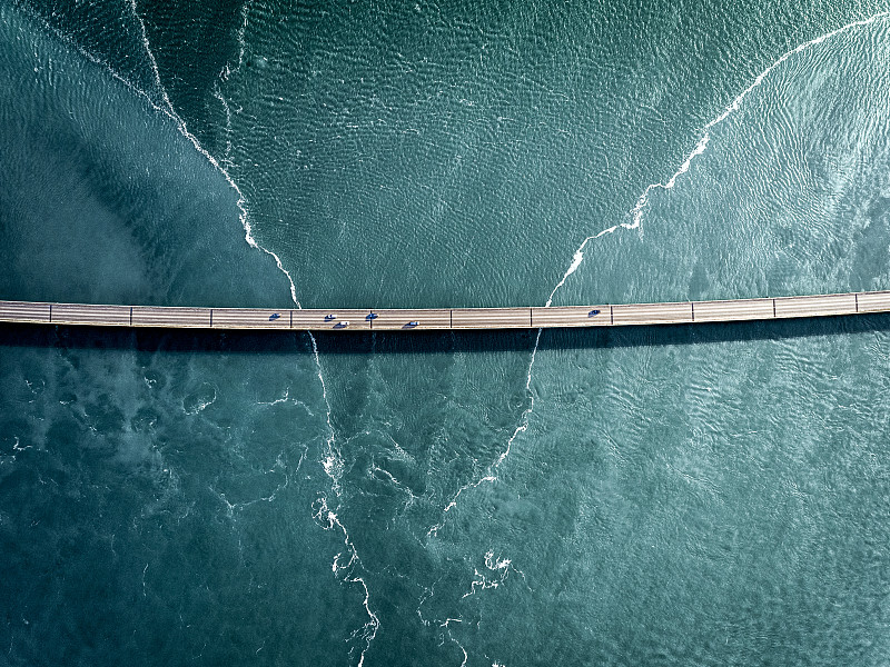 在一座桥上行驶在深蓝色的水面上图片下载