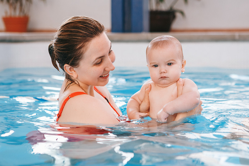 一个女人抱着一个男婴在游泳池里图片素材