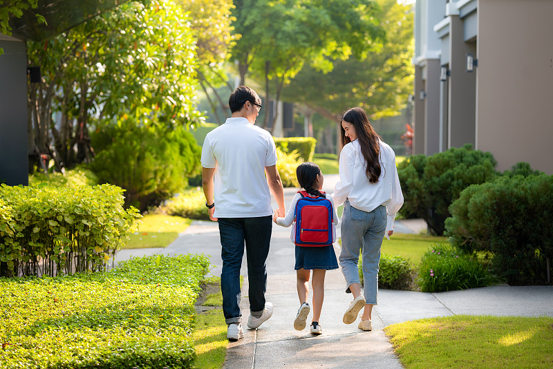 幸福的亚裔家庭，父亲，母亲和女儿学前班学生步行上学。课的开始。秋天的第一天。为人父母或爱与联结的表达概念。图片素材