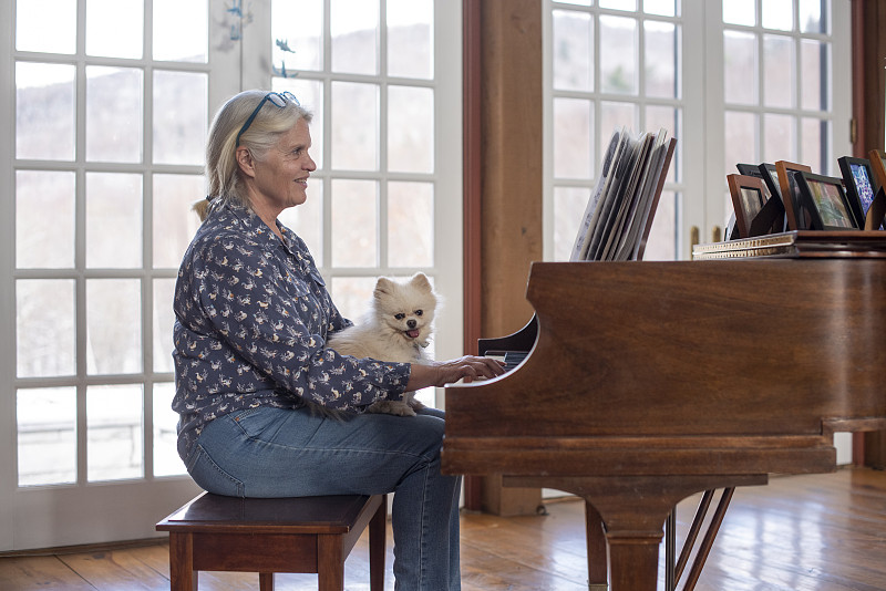 老人在弹钢琴，狗坐在她的腿上图片下载