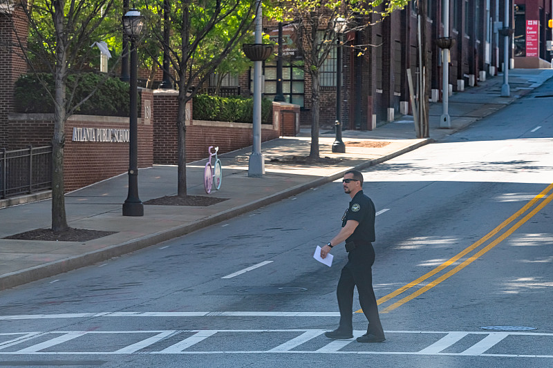 警察，在乔治亚州亚特兰大的公立学校大楼旁，一名警察正在过马路图片下载
