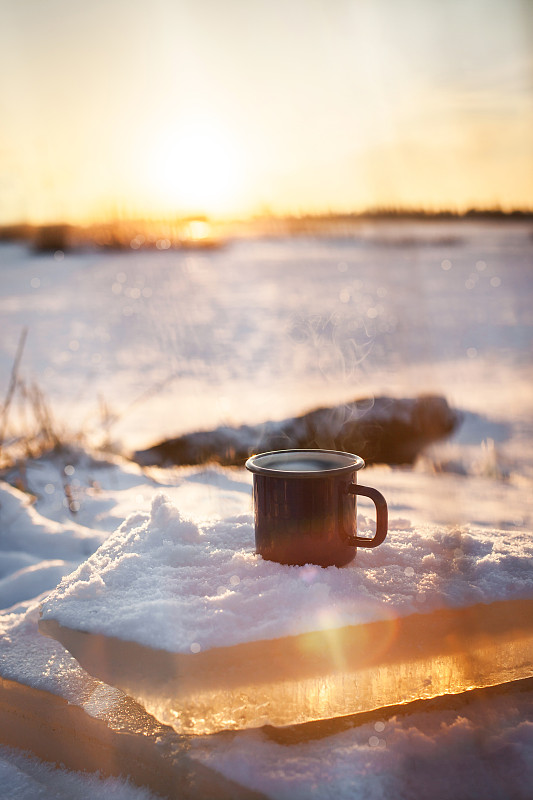 一杯热腾腾的咖啡上了雪，背景是冬日阳光明媚的日子图片素材