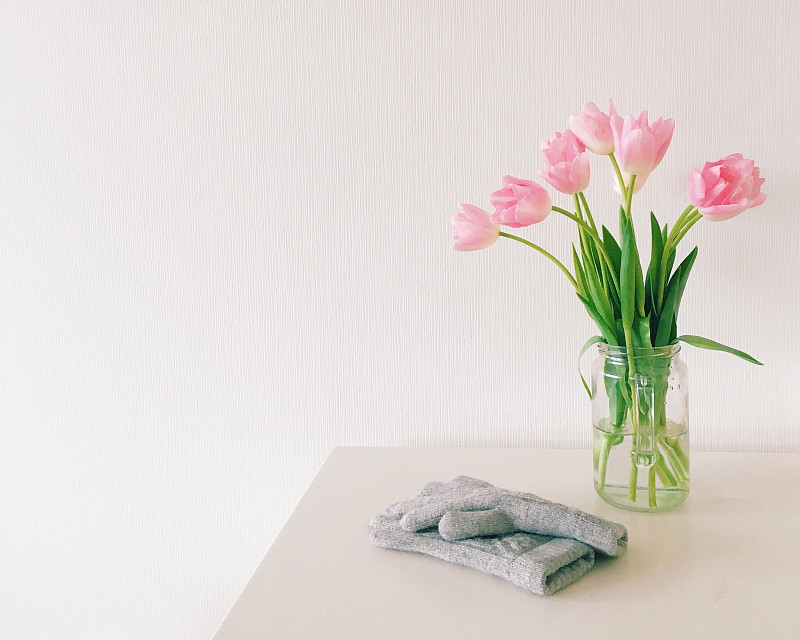 手套的特写:靠墙的桌子上的粉色花瓶图片素材