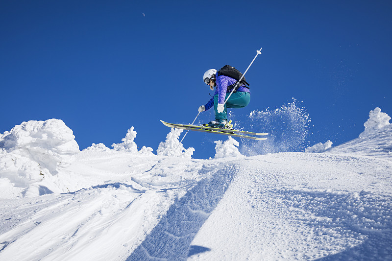 女子在滑雪日的跳跃图片下载