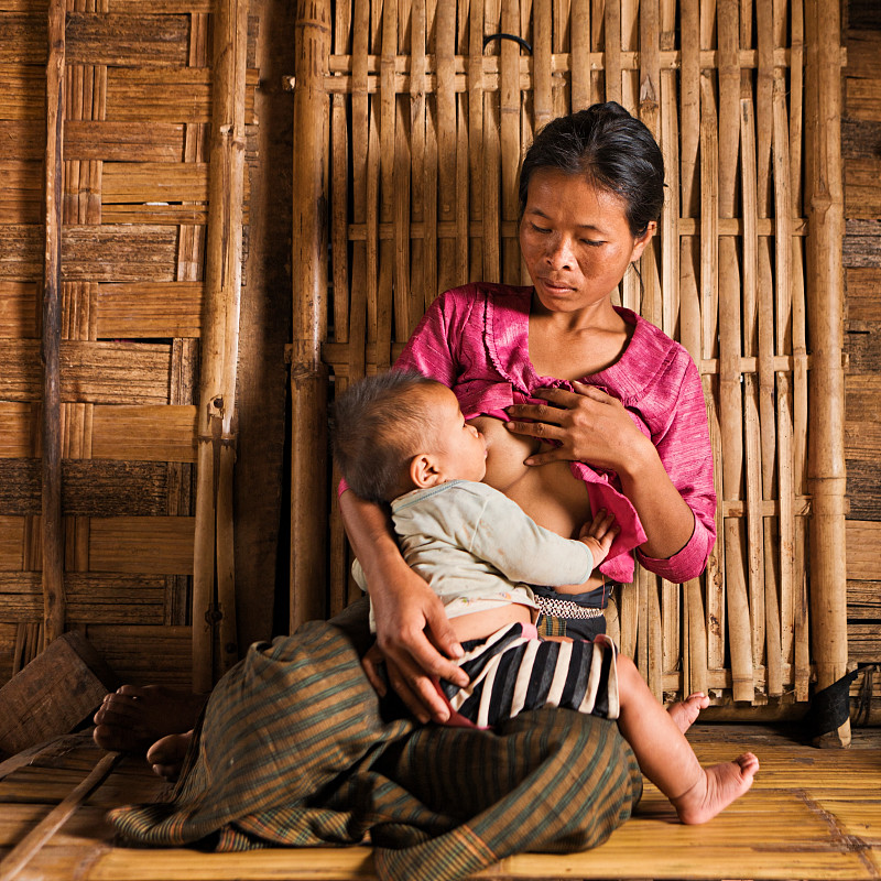 老挝北部年轻妇女母乳喂养婴儿的肖像图片素材