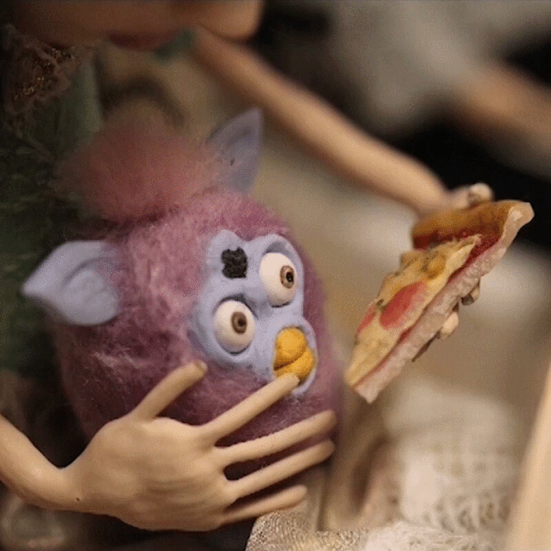小女孩试图喂她的填充娃娃一片披萨的木偶形象，定格动作效果图片下载