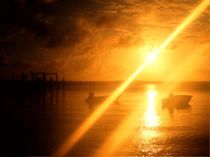 两艘摩托艇停泊在日落时分的海上，牙买加内格里尔图片下载