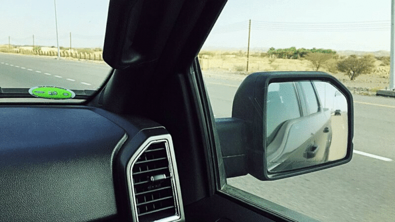 汽车在沙漠公路上行驶，后视镜中可以看到汽车，阿曼图片下载