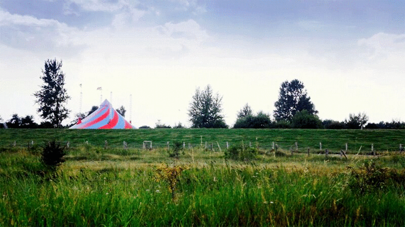 在绿野上骑着自行车的人在马戏团帐篷旁图片下载