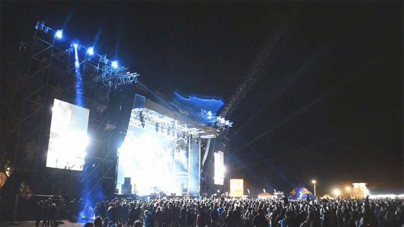 人群在音乐节的夜晚，蓝色的灯光和雨图片下载