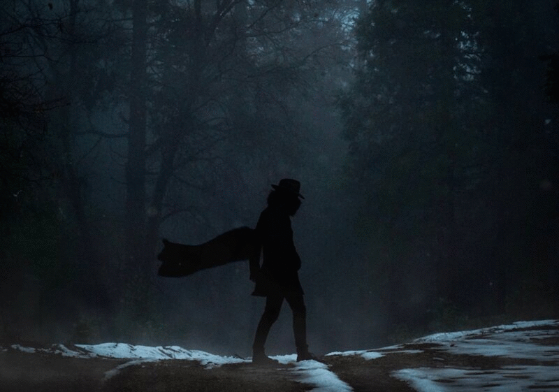 神秘反派的剪影在帽子和飘动的斗篷在森林在降雪期间图片下载
