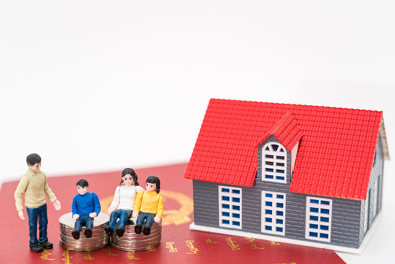 玩具人偶和房子模型放在房产证上——房地产概念图片图片下载