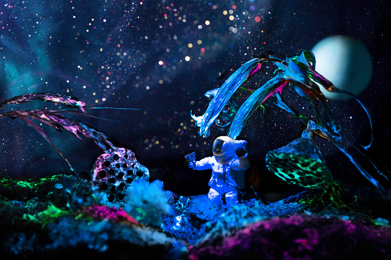 创意宇航员在宇宙中探索荧光星球的自然风景图片下载