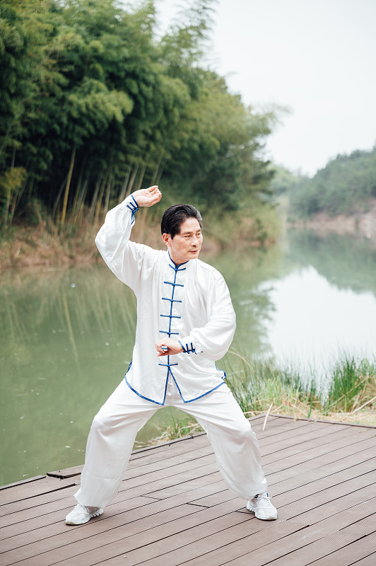 亚洲老年男性在湖边打太极拳图片下载