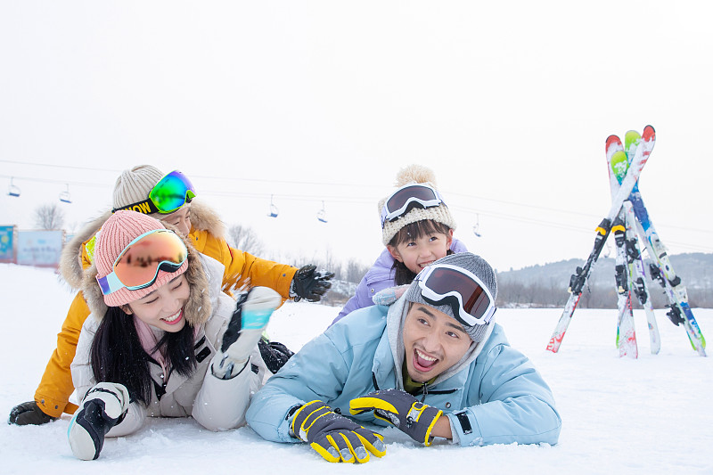 快乐的一家四口趴在雪地上玩耍嬉戏图片下载