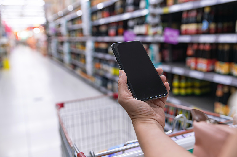 中年女性拿着手机在超市购物图片素材