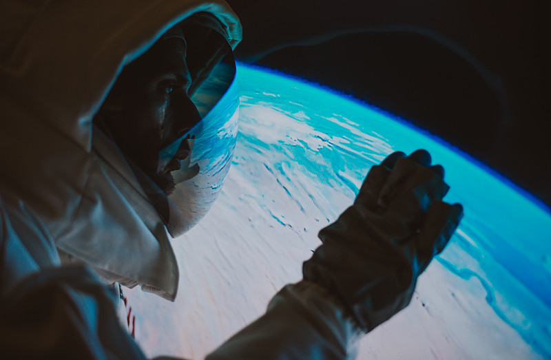 宇航员在宇宙飞船中，背景是地球图片素材