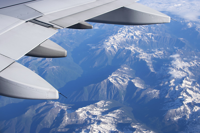 裁剪图像的飞机机翼飞过雪山，米兰，意大利图片素材