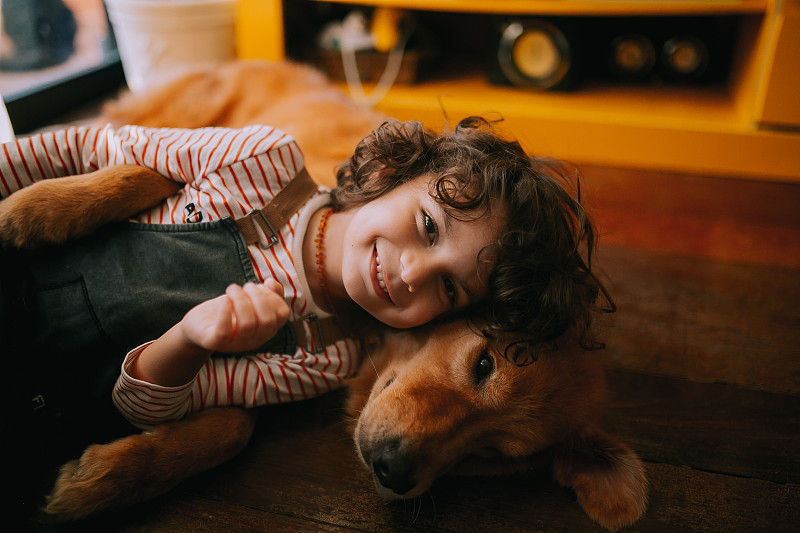 小白种人男孩躺在室内的金毛寻回犬的肖像，维多利亚，不列颠哥伦比亚省，加拿大图片素材