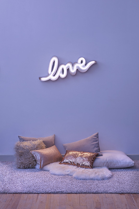 拼有“LOVE”字样的霓虹灯和地板上的各种坐垫图片素材