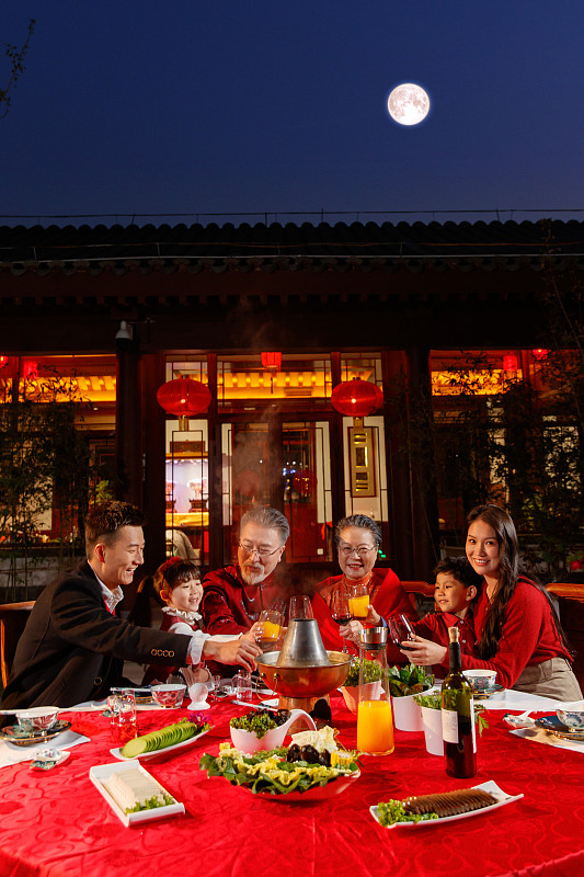 东方家庭在中式庭院内干杯庆祝新年图片下载