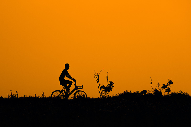 夕阳下骑自行车的人的剪影图片下载