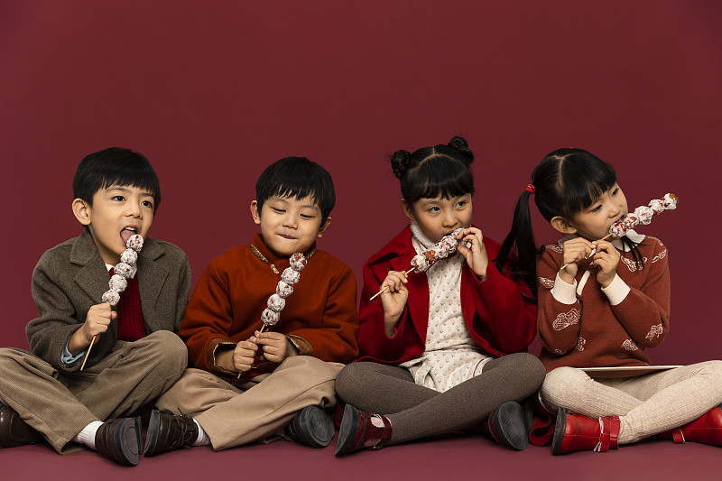 儿童庆祝春节系列：欢乐的小男孩和小女孩们吃糖葫芦庆祝新春图片下载