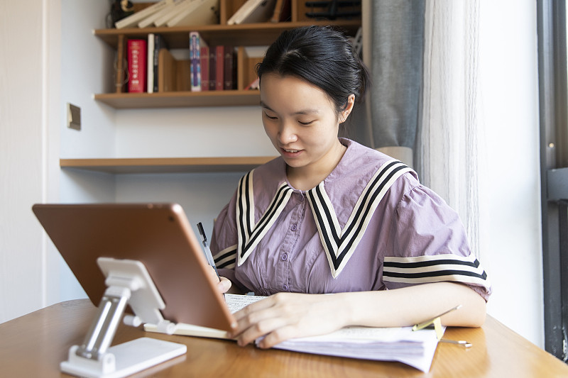 一个年轻中国女人在家里用平板电脑学习图片下载