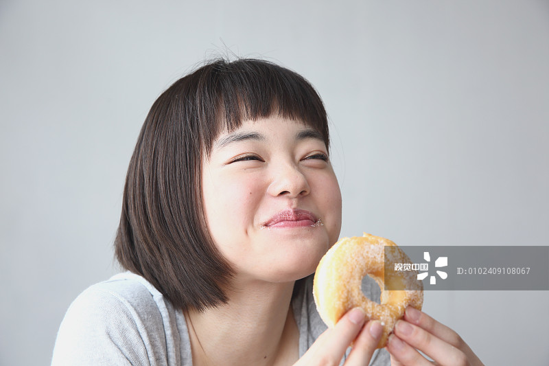 年轻的日本女人在通风的房间吃甜甜圈图片下载