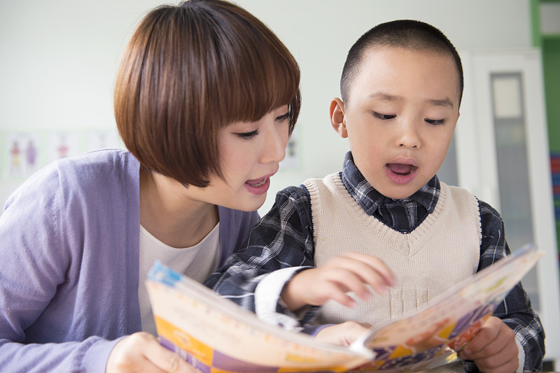 Kindergarten teacher and boy reading图片下载