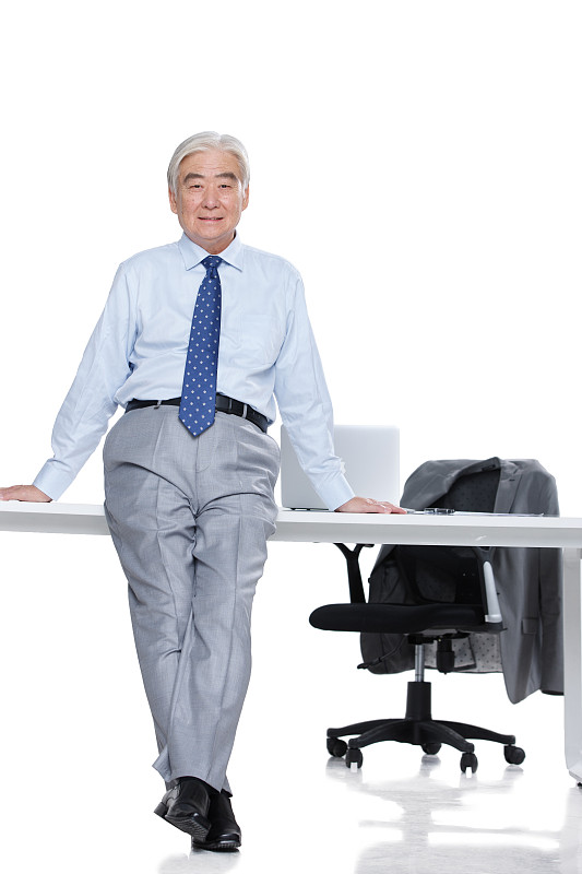 成功的老年男人斜靠在办公桌上图片素材