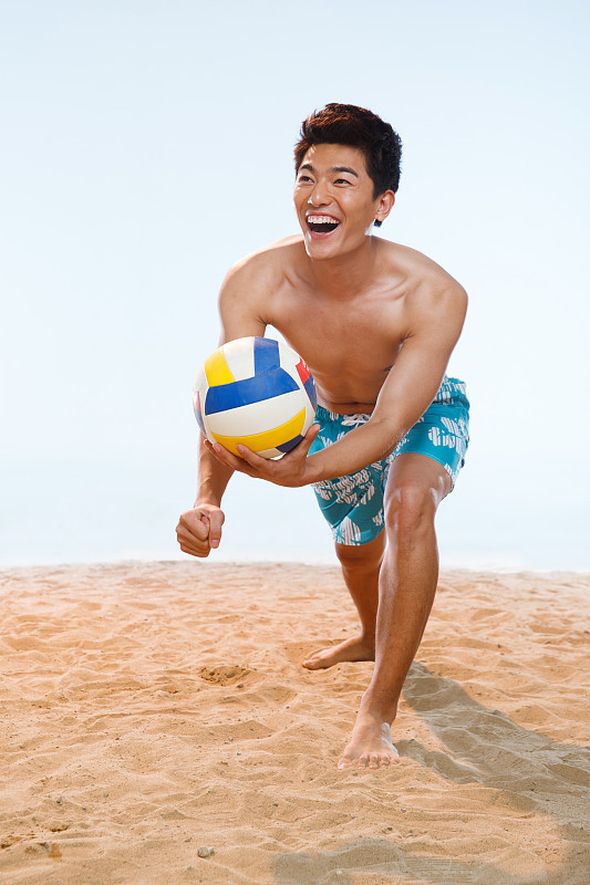 海滩上打球的青年男人图片下载