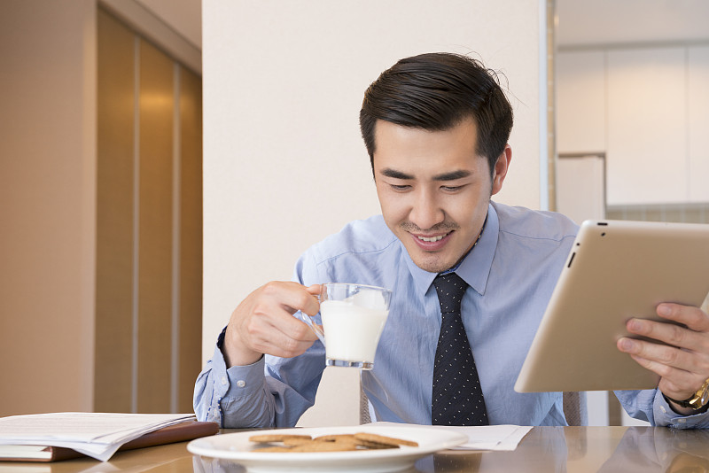 Young man using laptop at breakfast图片下载