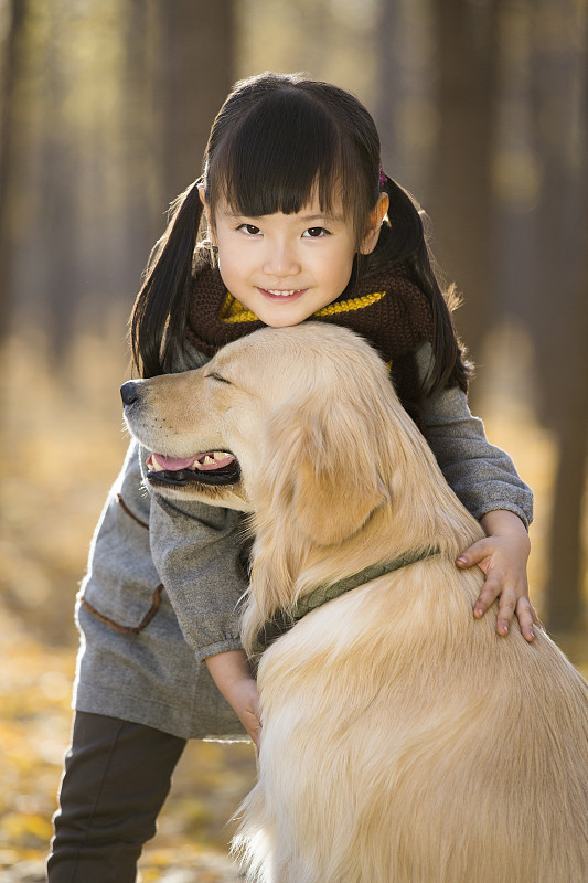 小女孩和宠物狗在秋日树林里玩耍图片