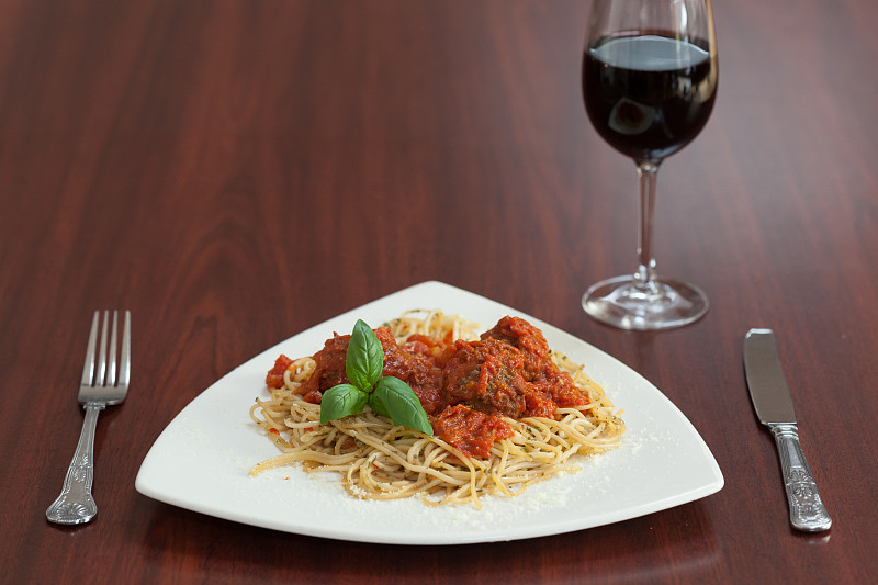 意大利面和肉丸与红酒在木桌上的正面视图图片下载