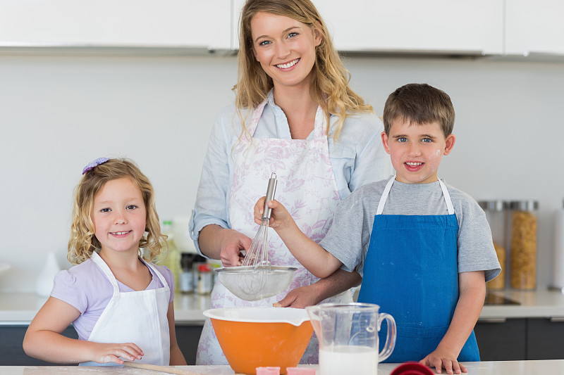 母亲与儿子和女儿在厨房台面上烤饼干的肖像图片下载
